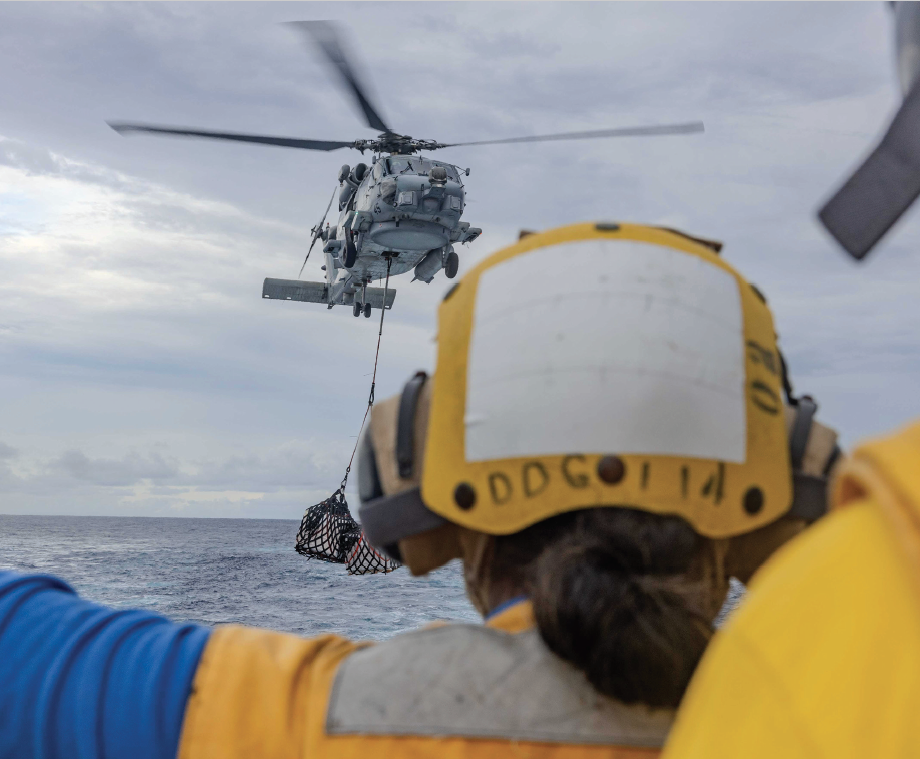 Boatswain’s Mate Seaman Tyatiana Finley signals to MH-60R assigned to Helicopter Maritime Strike Squadron 49 detatchment 4 “HighRollers” as it delivers supplies to flight deck of guided-missile destroyer USS Ralph Johnson during vertical replenishment with dry cargo andammunition ship USNS Cesar Chavez, underway in Indian Ocean, April 26, 2025 (U.S. Navy/Hannah Fry)